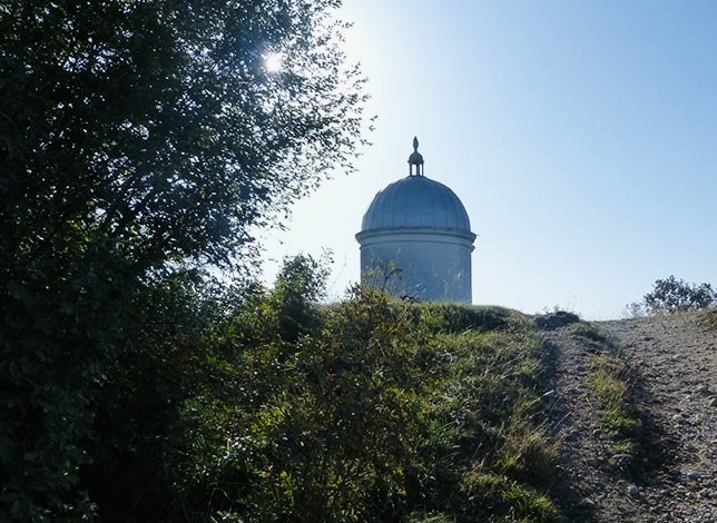 the chapel of San Giorgio against a blue sky with tree and trail in foreground